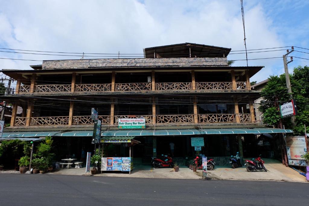 a large wooden building with motorcycles parked in front of it at Koh Chang Hut Hotel in Ko Chang