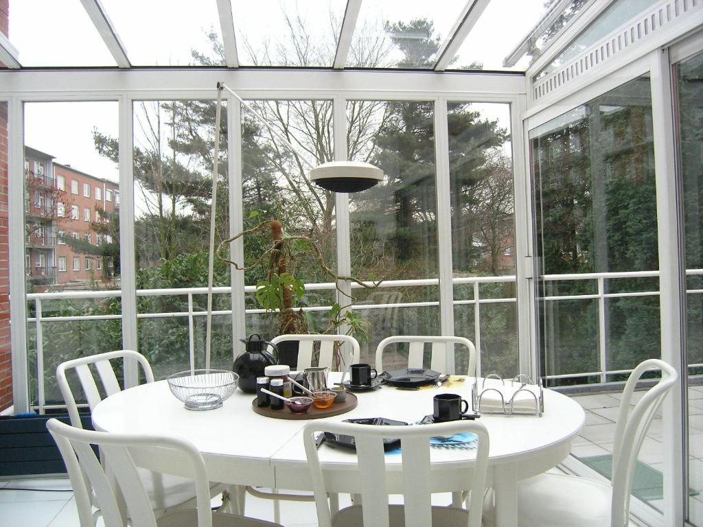 un salón acristalado blanco con una mesa y sillas blancas en B&B Middelheim, en Amberes