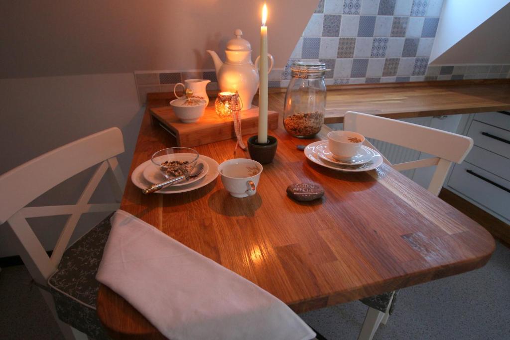 een houten tafel met twee stoelen en een kaars erop bij Ferienwohnung Spatzennest in Frankenberg