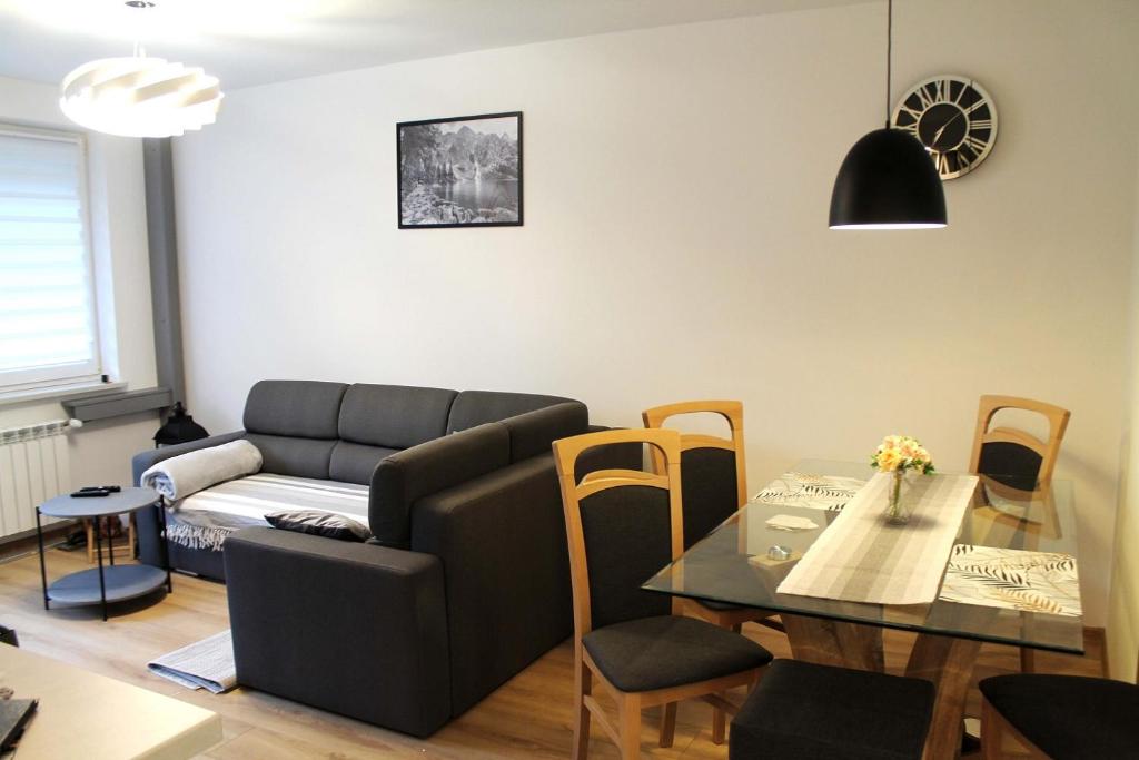 ein Wohnzimmer mit einem Sofa und einem Tisch in der Unterkunft Apartament Perełka Przy Krupówkach in Zakopane