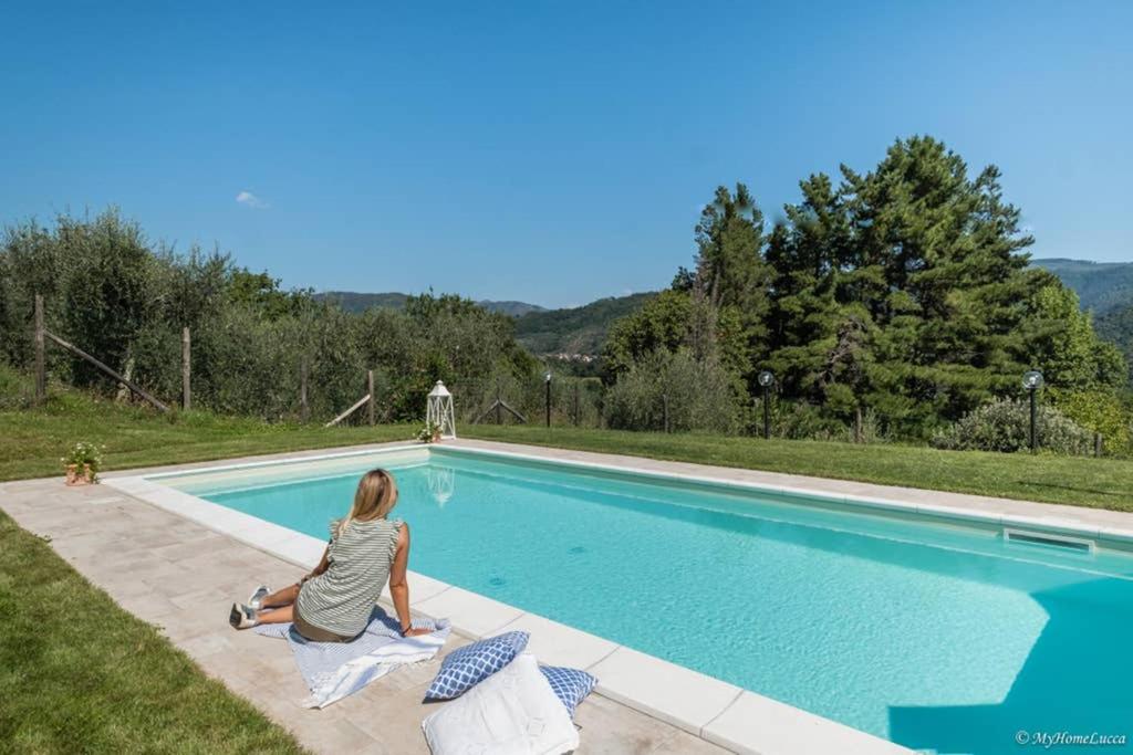 una mujer sentada junto a una piscina en Alla Bella Aurora with Amazing POOL in Tuscany, en Lucca