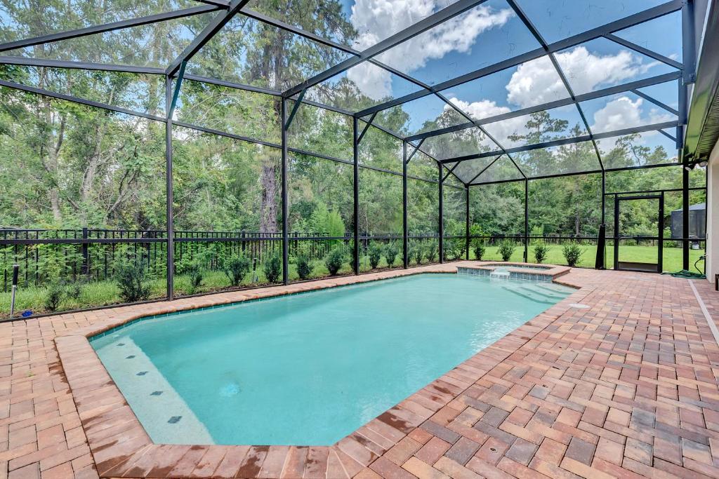 an indoor pool in a glass house with a brick patio at Villa W Pool Movie Theater Game RoomSleeps 20 in Kissimmee