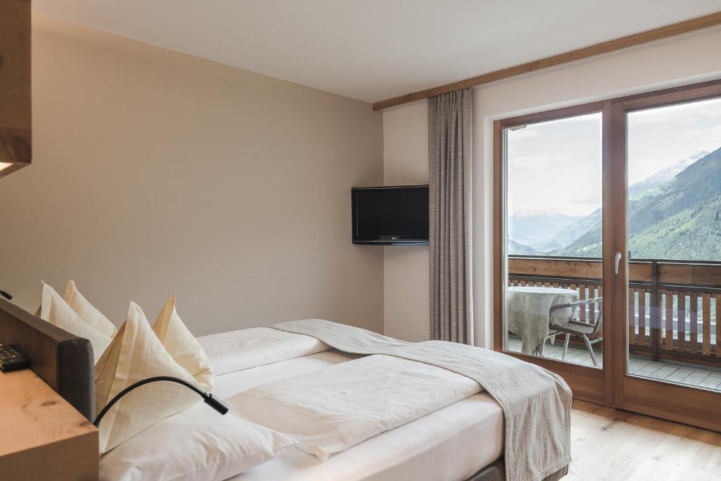 a hotel room with a bed and a balcony at Naturhotel Gruberhof in Schenna