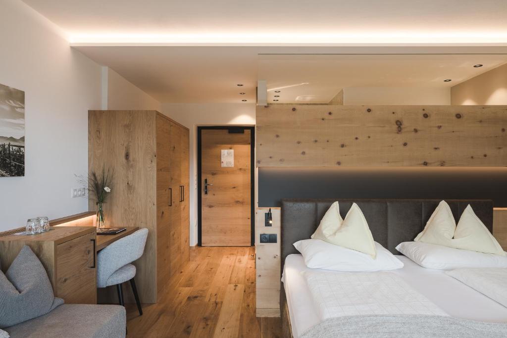 a bedroom with a bed and a desk and a chair at Naturhotel Gruberhof in Schenna