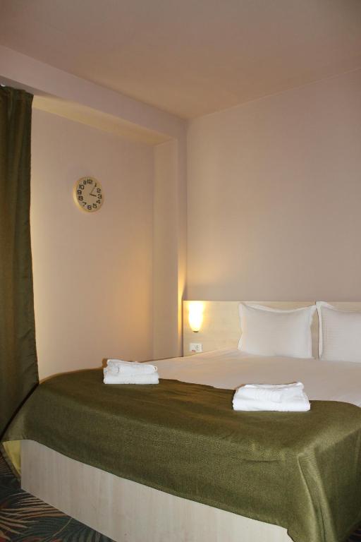 a bedroom with a bed with a clock on the wall at Stop Hotel in Braşov