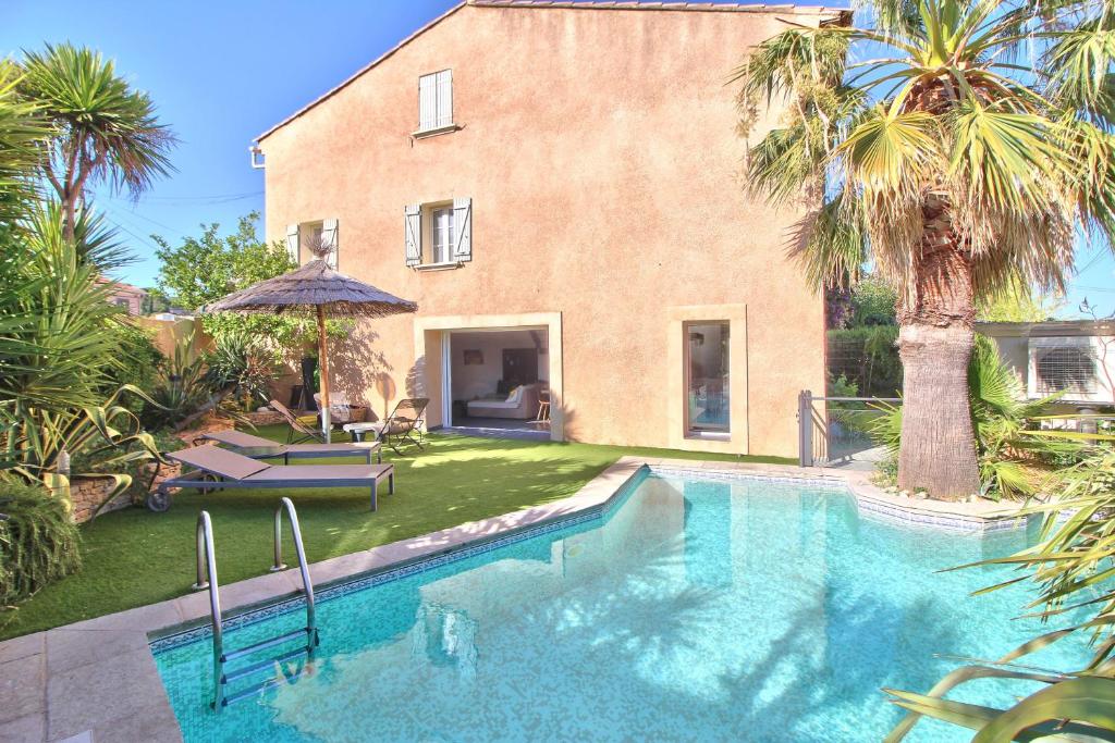 une piscine en face d'une maison avec des palmiers dans l'établissement Maison avec piscine et jardin- 4 chambres 8 pers, à Cuers