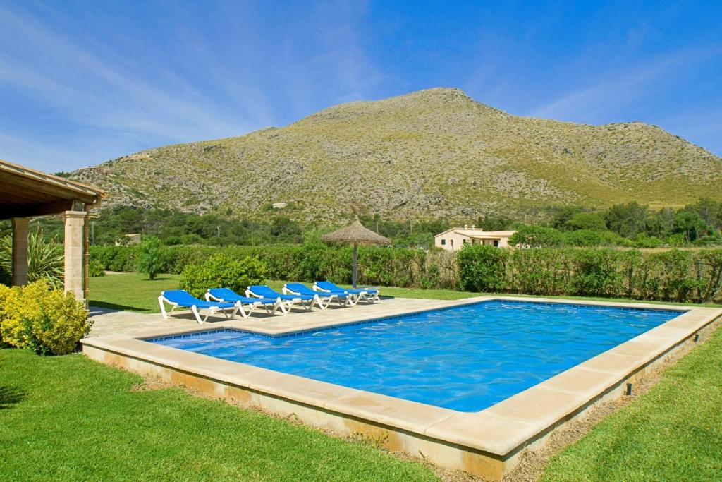 einem Pool mit Stühlen und einem Berg im Hintergrund in der Unterkunft Villa Pedra Vista in El Port