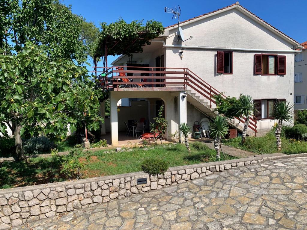 a large white house with a stone wall at Apartments Viola in Šilo