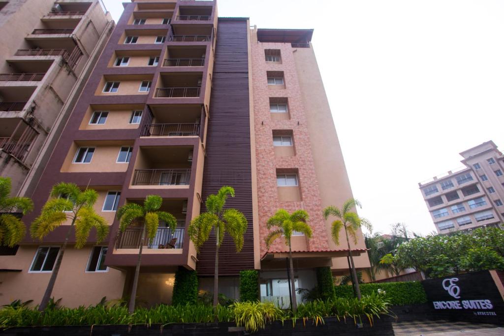 un edificio alto con palme di fronte di Encore Suites Goa a Panaji