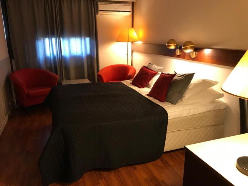 Habitación de hotel con cama y silla roja en Hotel Carneval, en Suonenjoki