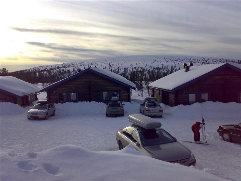 Ski-in ski-out Sälen Högfjället 4-6 bäddar في سالن: مجموعة من السيارات تقف في الثلج بجوار كابينة