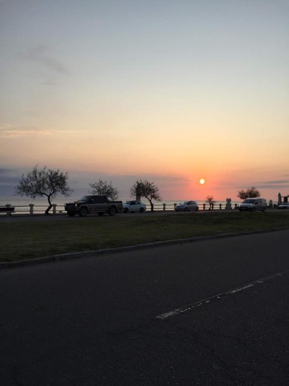 una puesta de sol con coches estacionados al costado de una carretera en Lo de IRMA, en Piriápolis