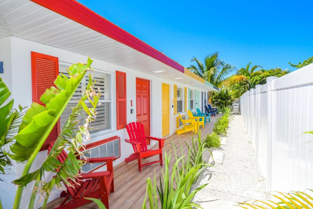 een kleurrijk huis met rode stoelen op een terras bij Captain’s Quarters at Anna Maria Island Inn in Bradenton Beach