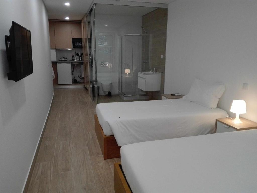 a small bedroom with two beds and a shower at Central Suites 2 Quarto A in São João da Madeira