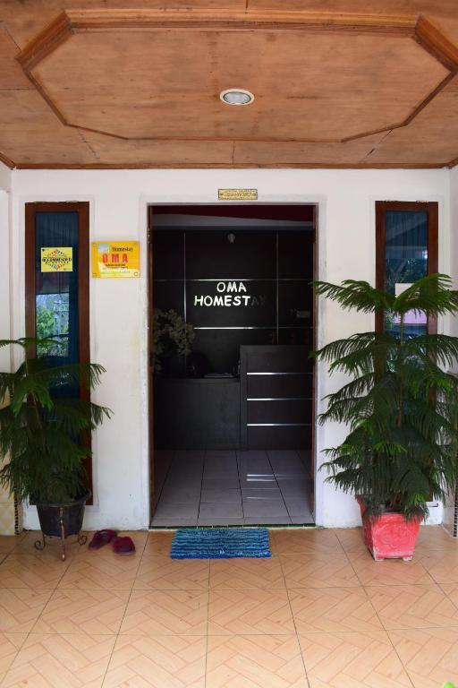 una puerta delantera de una casa con un cartel en ella en OMA Homestay, en Sawahlunto