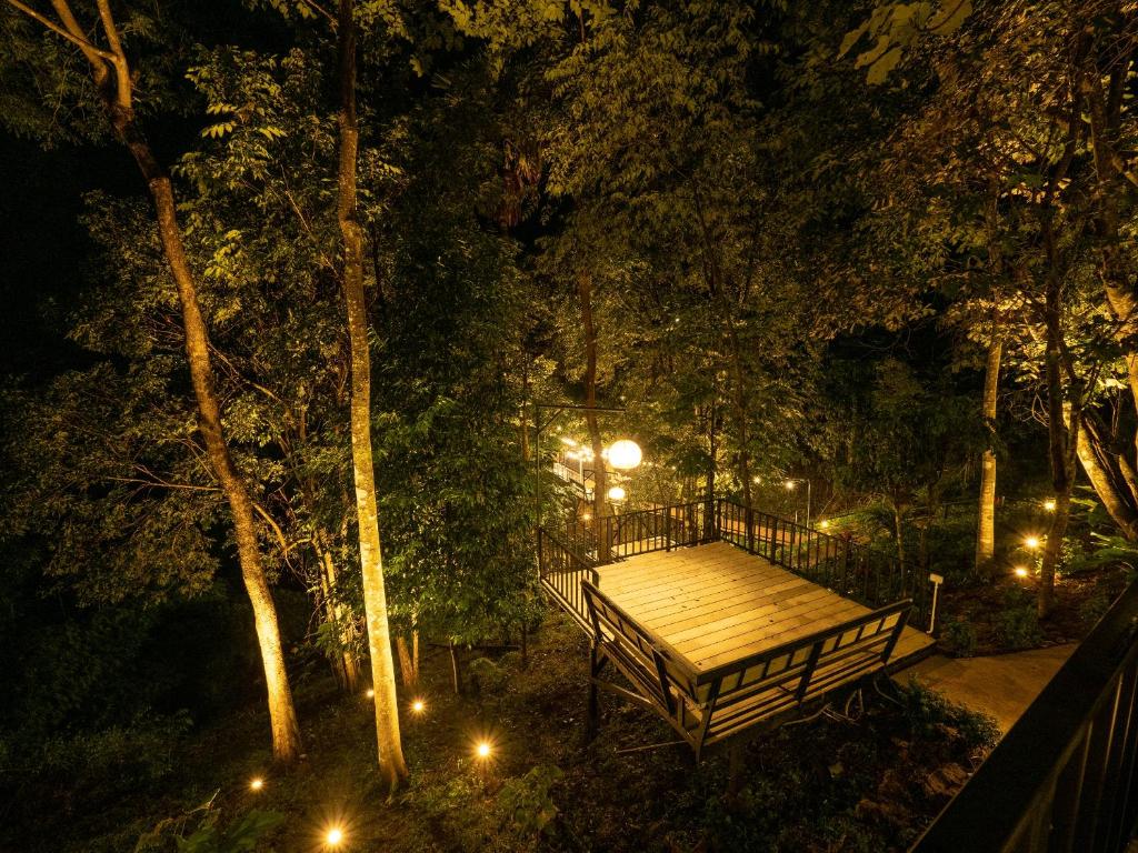 ławka w parku w nocy z oświetleniem w obiekcie บ้านรักษ์วนา w mieście Khao Kho