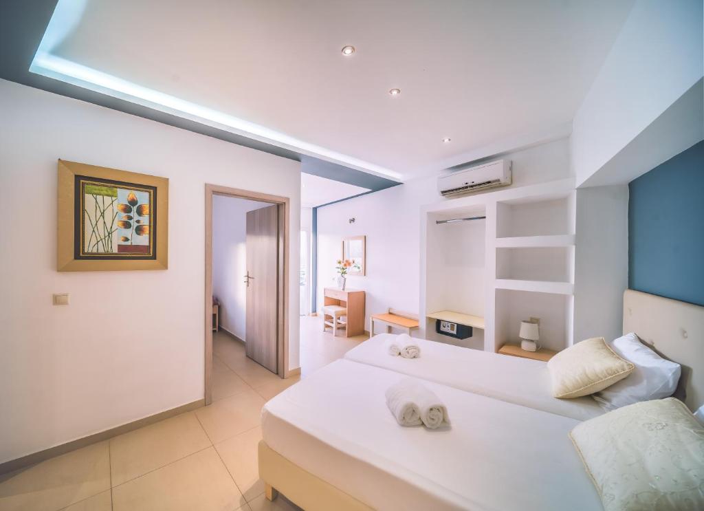 - une chambre avec un grand lit blanc et des serviettes dans l'établissement Laplaya Beach, à Mália