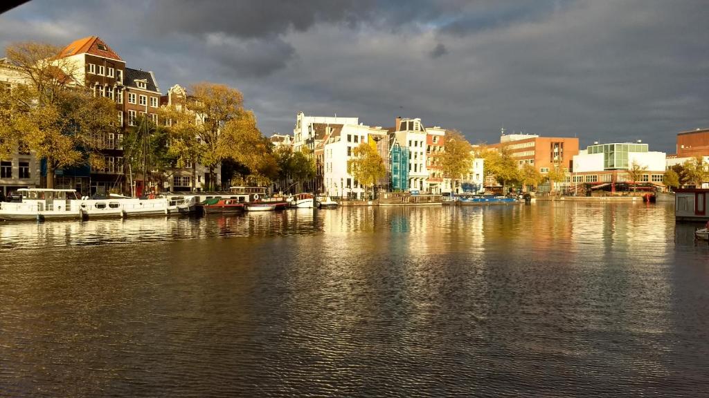 a river with boats in a city with buildings at Rembrandt Square Boat in Amsterdam