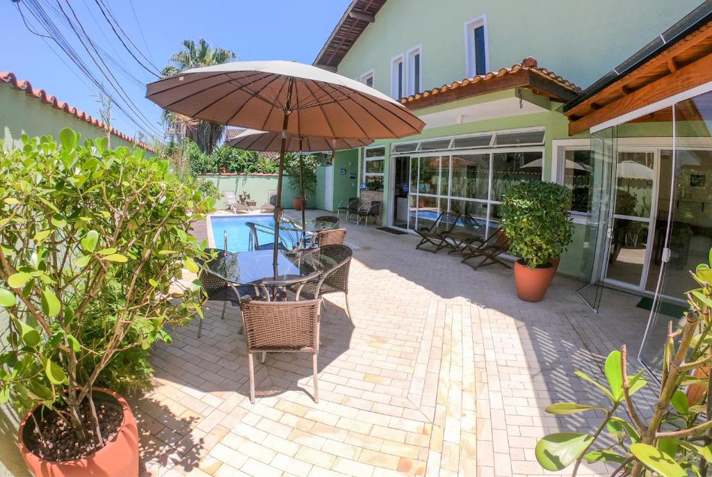 a patio with an umbrella and chairs and a pool at Pousada Etoile in Juquei