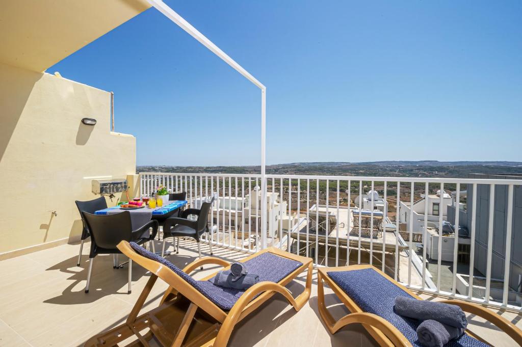 uma varanda com cadeiras e uma mesa no telhado em Summer Breeze apartment with terrace with Panoramic views - by Getawaysmalta em Mellieħa