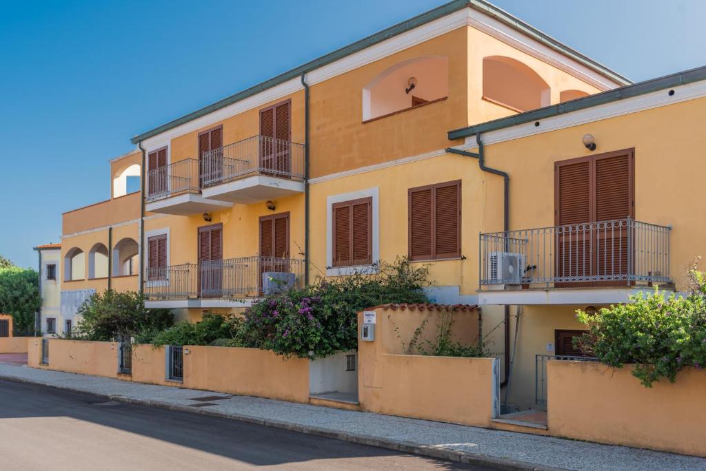 ein gelbes Gebäude mit Balkonen auf einer Straße in der Unterkunft Residence Le Pavoncelle in Santa Teresa Gallura