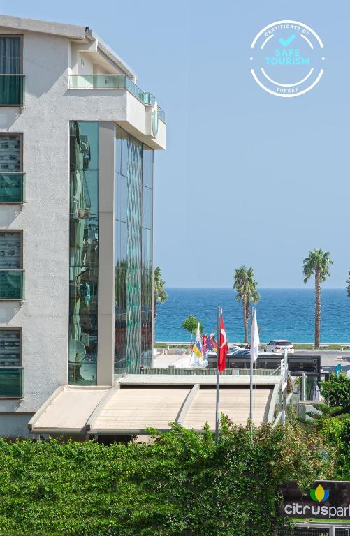 a building with the ocean in the background at Citrus Park Hotel in Antalya