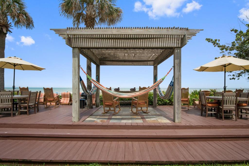 a hammock on a deck with tables and chairs at Beach Place Guesthouses in Cocoa Beach