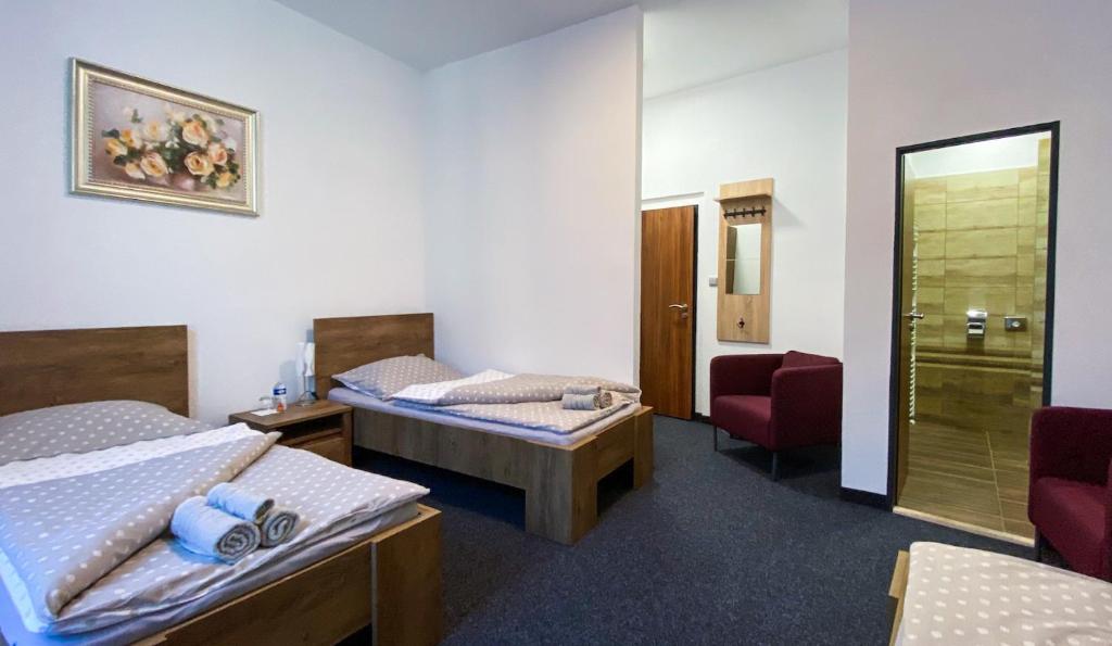 a hotel room with two beds and a chair at Hotel Sýkora in Křivoklát