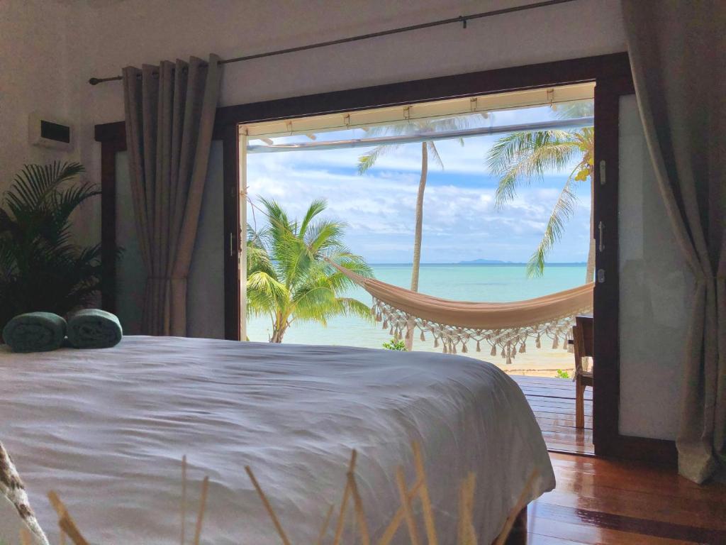 a bedroom with a bed and a view of the ocean at Mangata Boutique Bungalows in Srithanu
