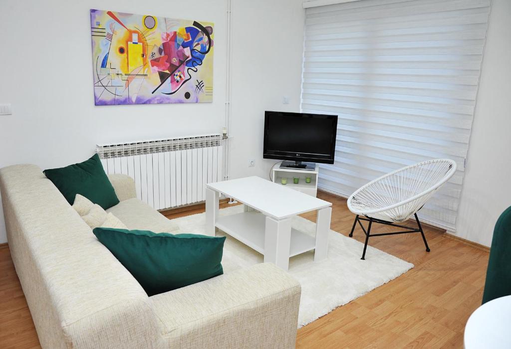 ein Wohnzimmer mit einem Sofa und einem TV in der Unterkunft Apartman Lizdek in Pale