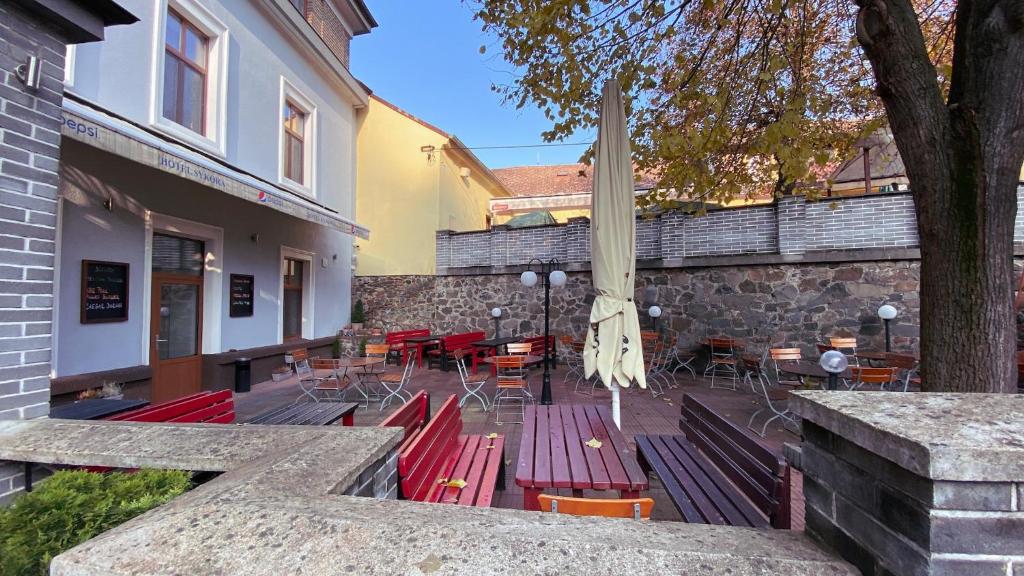 a patio with red benches and tables and chairs at Hotel Sýkora in Křivoklát