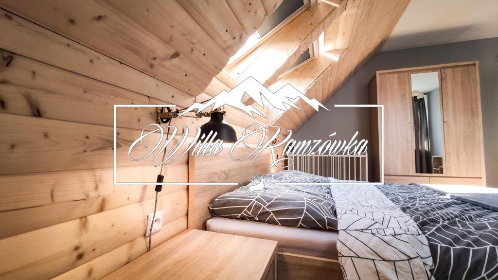 1 dormitorio con paredes de madera y 1 cama con cartel en Willa Ramzówka - Domek w Beskidzie Sądeckim, en Nowy Sącz