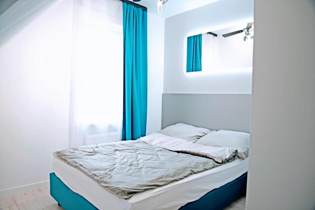 1 dormitorio con 1 cama con cortinas azules y ventana en KOMFORT WILLA, en Blizne Łaszczyńskiego