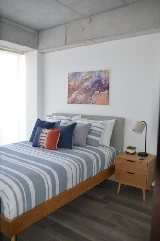 1 dormitorio con 1 cama con almohadas azules y blancas en Cozy Stays Cayala Apartments 3 en Guatemala