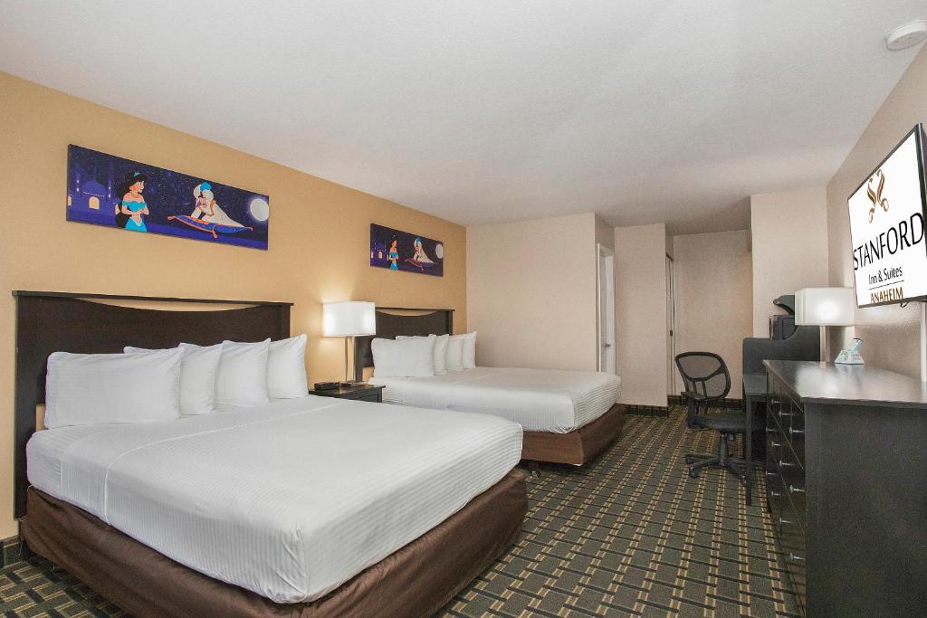 a hotel room with two beds and a desk at Stanford Inn & Suites Anaheim in Anaheim