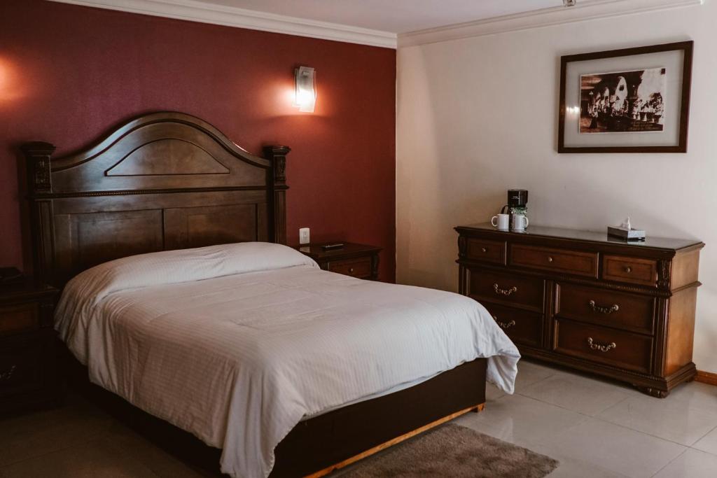 a bedroom with a large bed and a dresser at Hotel Puebla de Antaño in Puebla