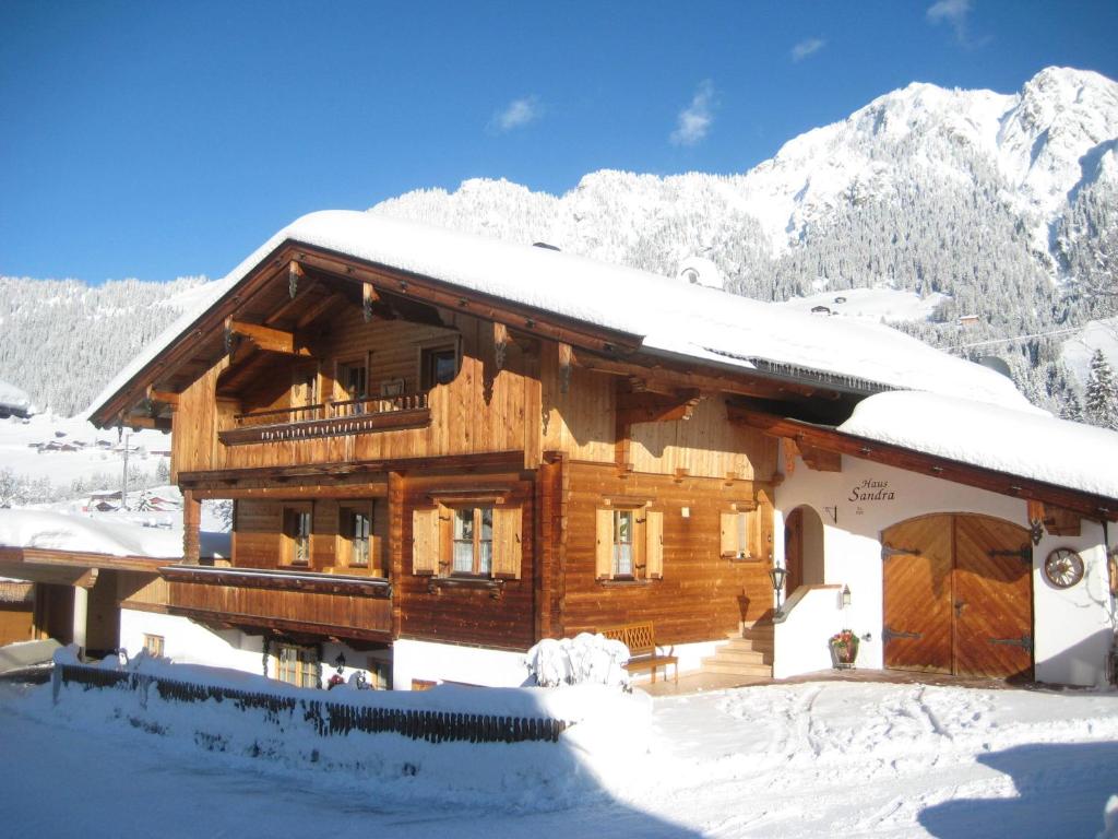 una cabaña de madera en la nieve con montañas en el fondo en Haus Sandra en Alpbach