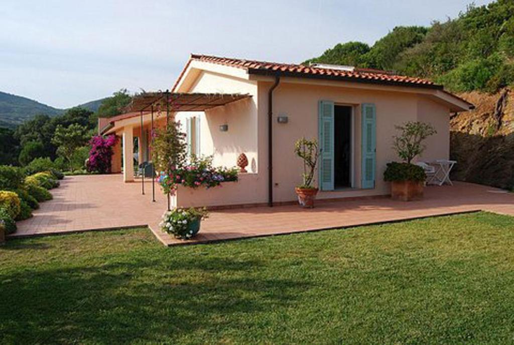a small house with a green lawn in front of it at Villa Gemma in Porto Azzurro