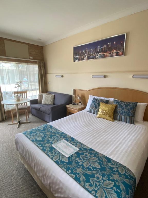 um quarto de hotel com uma cama grande e um sofá em Marriott Park Motel em Nowra