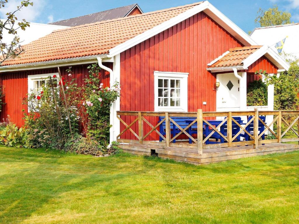 a red house with a wooden fence in a yard at One-Bedroom Holiday home in Hjältevad in Svenstorp