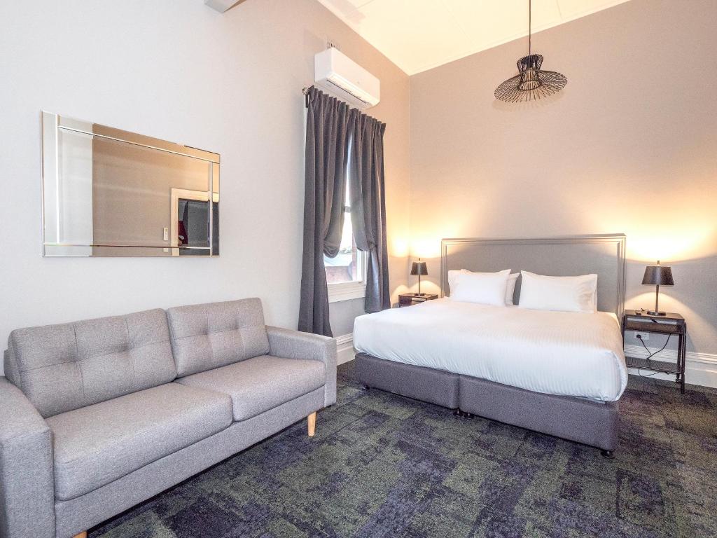 sypialnia z łóżkiem i kanapą w obiekcie Telegraph Hotel Numurkah w mieście Numurkah