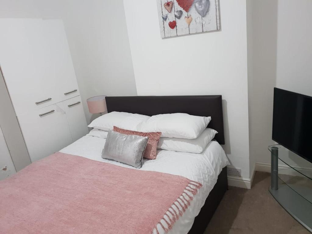 a bedroom with a bed with a pink blanket at Bambz Apartment 2 in Manchester