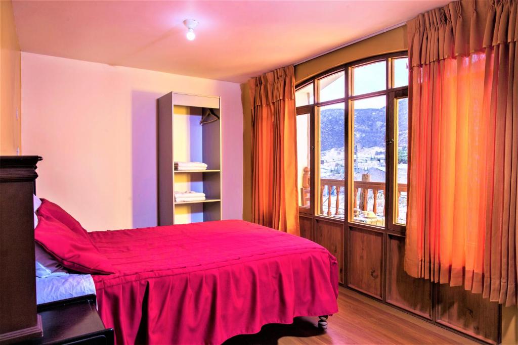 a bedroom with a red bed and a large window at Rumi Wasi in Chivay