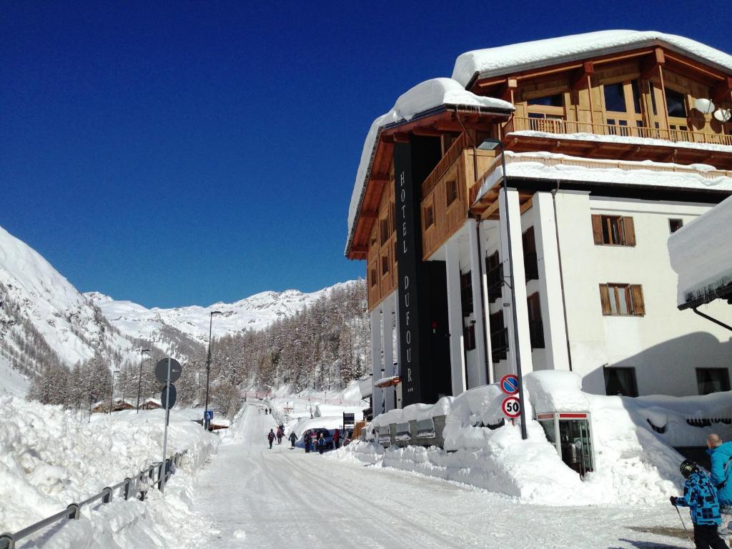 a building covered in snow next to a mountain at Hotel Dufour in Gressoney-la-Trinité