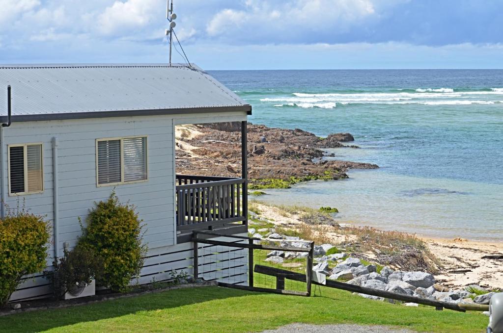 a house with a balcony overlooking the ocean at Tuross Beach Cabins & Campsites in Tuross Heads