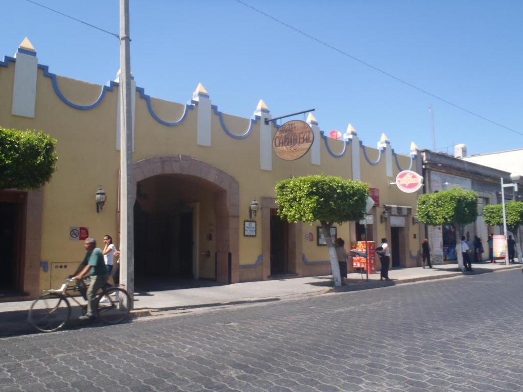 Un gruppo di persone che camminano per strada con un edificio di Hotel Casa Real Tehuacan a Tehuacán