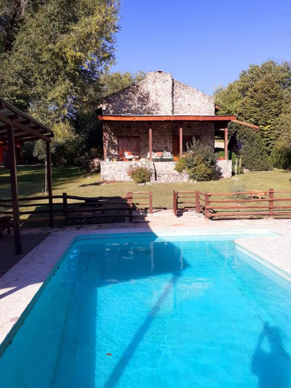 una piscina frente a una casa de piedra en Refugio de las Sierras en Villa General Belgrano