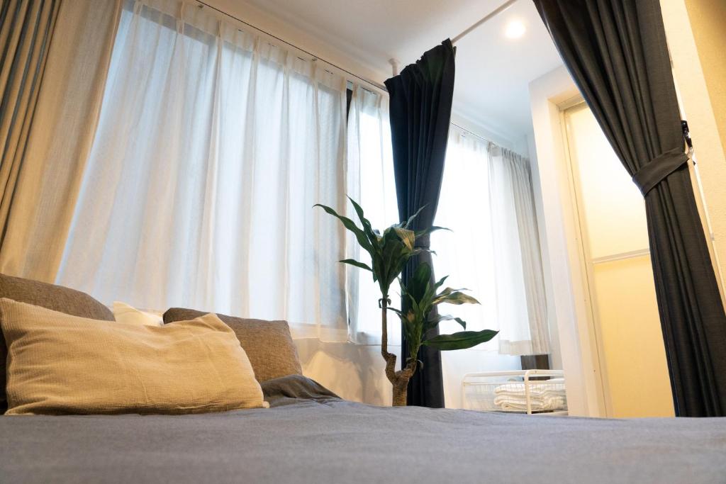 東京にあるHigashi Shinagawa Apartmentのベッドルーム1室(窓の前に植物が植えられたベッド1台付)