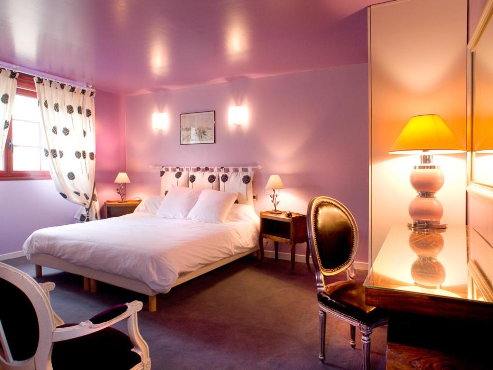 a bedroom with a white bed and two chairs at HOTEL LA COGNETTE A 25 Kilomètres de Châteauroux et 30 Kilomètres de Bourges in Issoudun