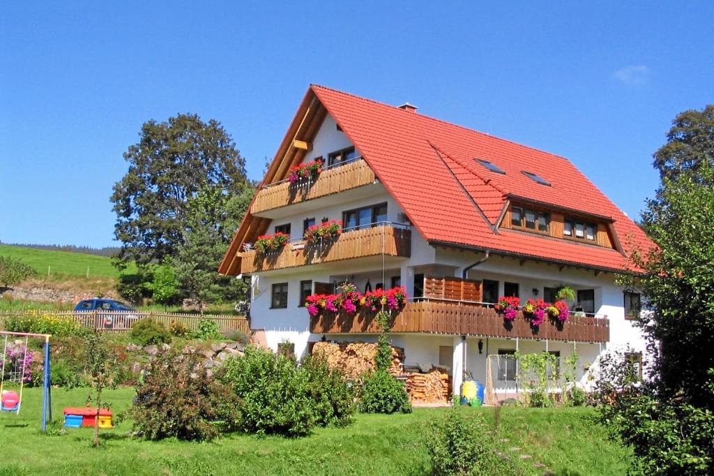 ein Haus mit einem orangenen Dach und Blumen auf den Balkonen in der Unterkunft Gästehaus Hundelbach in Lenzkirch